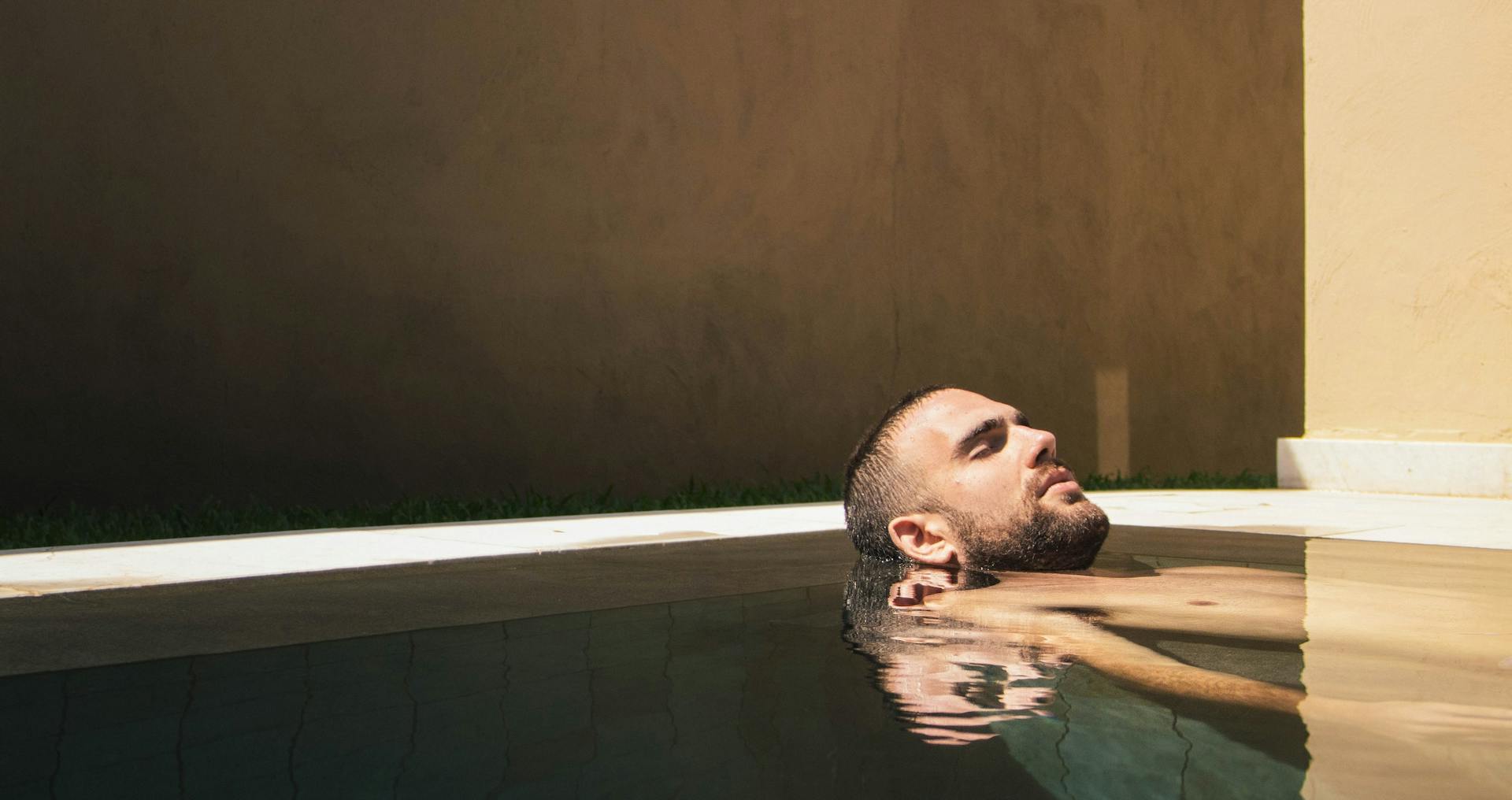 Homem relaxado na piscina com a cabeça fora da água